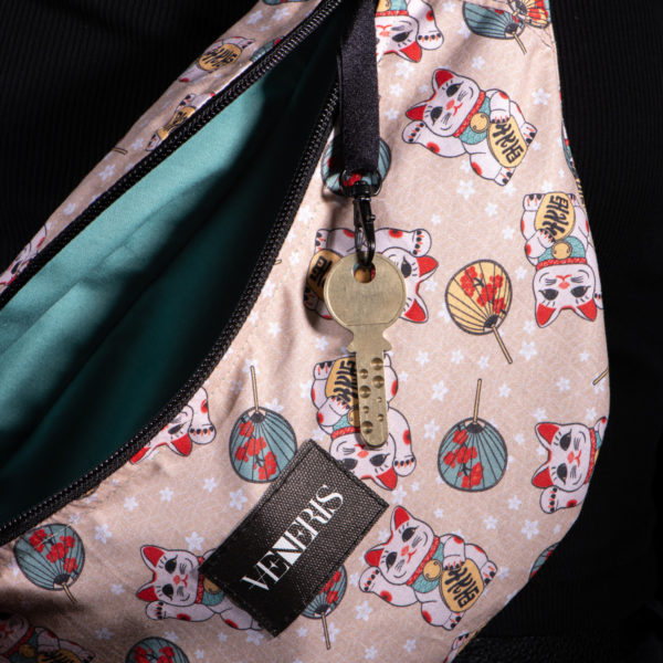 Sac banane light à motifs chats. Doublure turquoise. Collection Vigiliis Noctis Maneki. Crochet pour accessoire (clé, porte cartes...). Etiquette VENERIS noire. Sangle noire. Rivets de décoration.