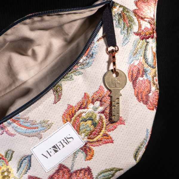 Sac banane à motifs fleurs. Doublure sable. Collection Vigiliis Noctis Stragula. Crochet pour accessoire (clé, porte cartes...). Etiquette VENERIS blanche. Sangle grise. Rivets de décoration.