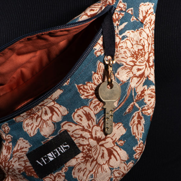 Sac banane à motifs fleurs. Doublure brun orangé. Collection Vigiliis Noctis Floridus. Crochet pour accessoire (clé, porte cartes...). Etiquette VENERIS noire. Rivets de décoration.