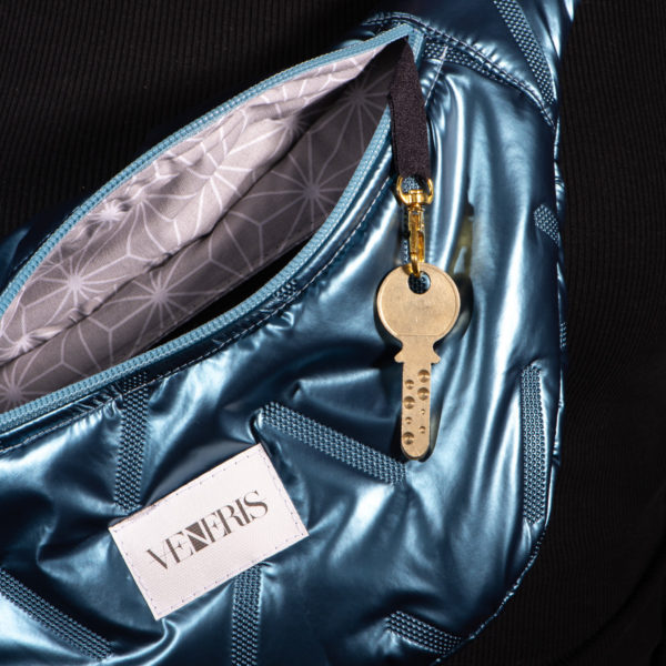 Sac banane en tissu matelassé métallisé. Doublure grise à motifs. Collection Vigiliis Noctis Blue Nebula. Crochet pour accessoire (clé, porte cartes...). Etiquette VENERIS blanche. Rivets de décoration.