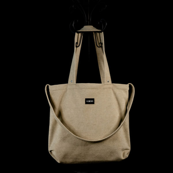Tote bag sable en velours côtelé (grosse côtes). Collection LET IT SNOW Cosy n°2. Trois anses réalisées avec le même tissu. Rivets de décoration à chaque extrémité des petites sangles. Ce modèle est conçu avec une troisième anse plus longue pour porter le sac aussi en bandoulière. Etiquette VENERIS noire.