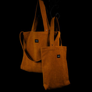 Tote bag ocre en velours côtelé (grosse côtes). Collection LET IT SNOW Cosy n°1. Anses réalisées avec le même tissu. Rivets de décoration à chaque extrémité des sangles. Grand modèle avec trois anses et petit modèle avec deux anses. Etiquette VENERIS noire.